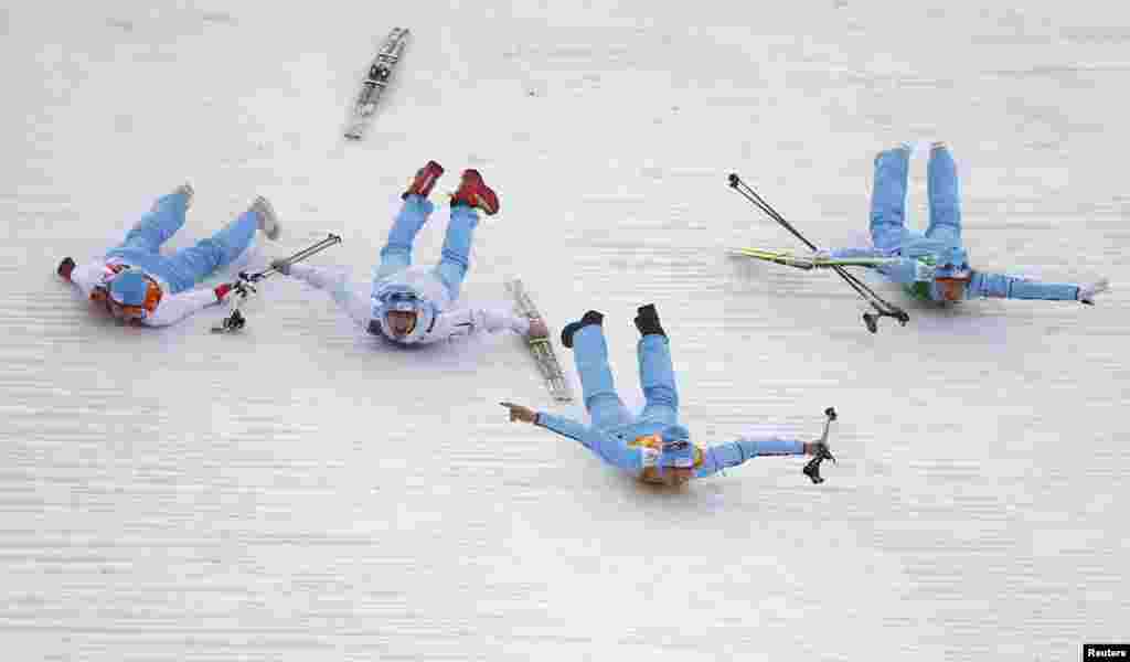 Norway's winning team members celebrate by sliding after the flower ceremony for the nordic-combined team event. (Reuters/Michael Dalder)