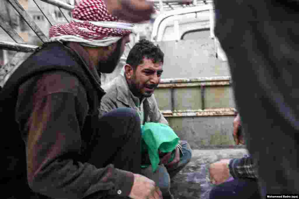 Bashar al-Toum (center) cries as he holds the body of one of his three dead children in a car on the way to the cemetery in the Syrian city of Douma. At least 13 were killed, including six children, due to bombing on the rebel-held city. (epa/Mohammed Badra)