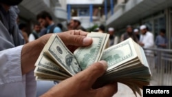 A money changer counts U.S. dollar banknotes at money change market in Herat province, Afghanistan June 3, 2018. Picture taken June 3, 2018. REUTERS/Jalil Ahmad