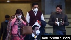 People wearing protective masks walk out of a Pakistan-based Chinese company in Islamabad amid fears over the coronavirus.