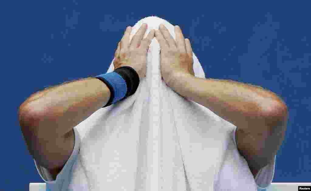 Ernests Gulbis of Lativa holds a towel over his head during a break in play in his men's singles match against Sam Querrey of the United States on January 15.