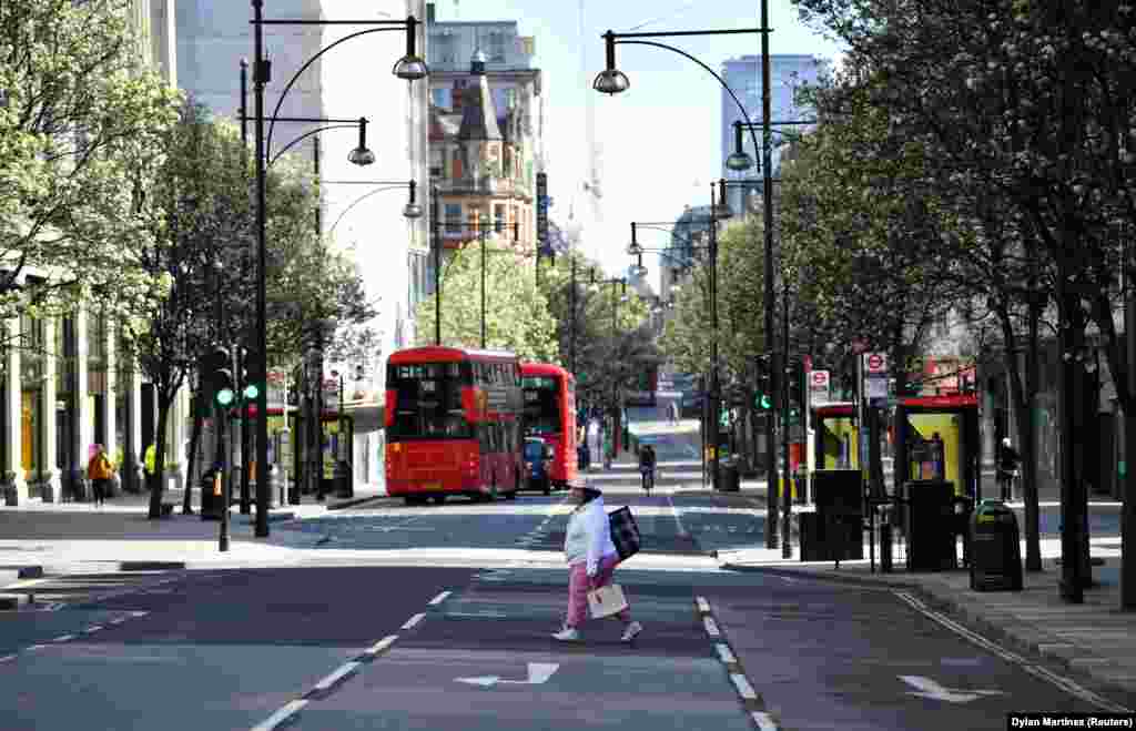 UK - A woman crosses Oxford Street as the spread of coronavirus disease (COVID-19) continues in London, 24Mar2020