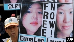 An activist holds up pictures of journalists Laura Ling and Euna Lee, who were detained in North Korea, at a rally in Seoul.