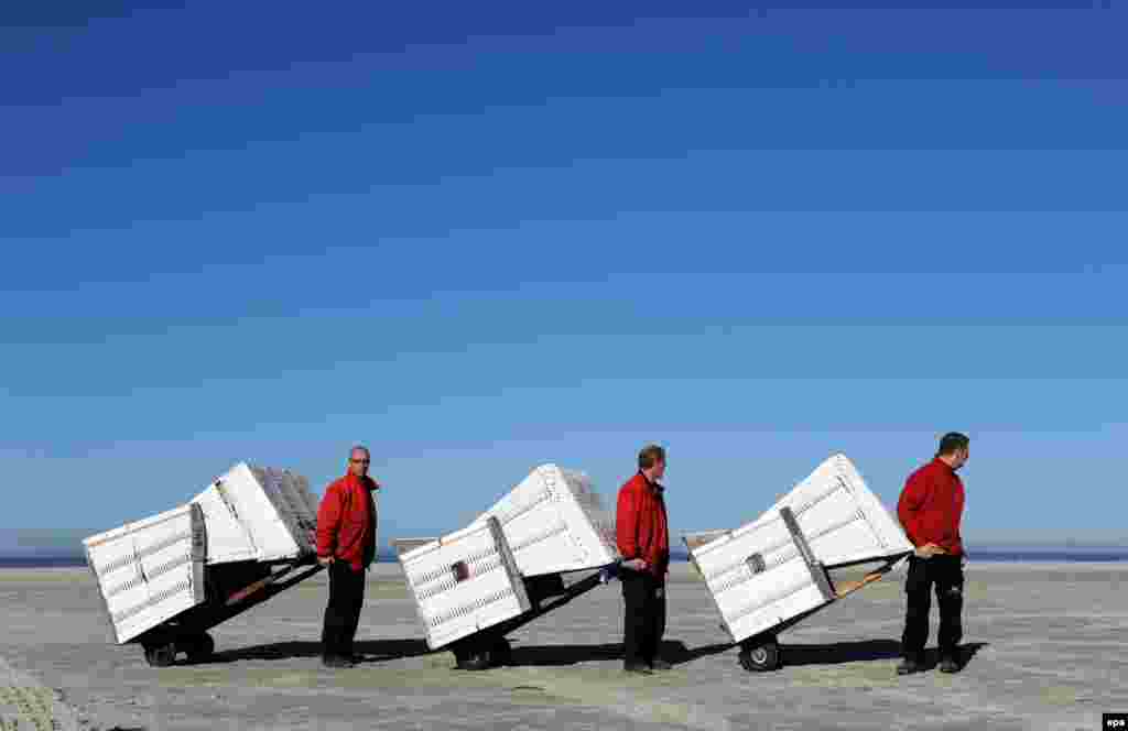 Staff members of the local tourist office transport deckchairs to the North Sea beach of St.Peter-Ording, Germany, on March 12. (epa/Karsten Rehder)