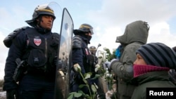 Pamje e mëparshme e policëve dhe migrantëve në kampin e njohur me emrin "xhungël" në Kale të Francës