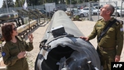 Purtătorii de cuvânt ai armatei israeliene lângă una din rachetele balistice lansate de Iran, care a căzut pe teritoriul Israelului.