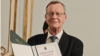 Klaus Bochmann, președintele Institutului Moldova Leipzig, la evenimentul de aniversare a 20 de ani de la fondarea organizației, cu o diplomă de excelență din partea Universității de Stat din Moldova, Chișinău, februarie 2026