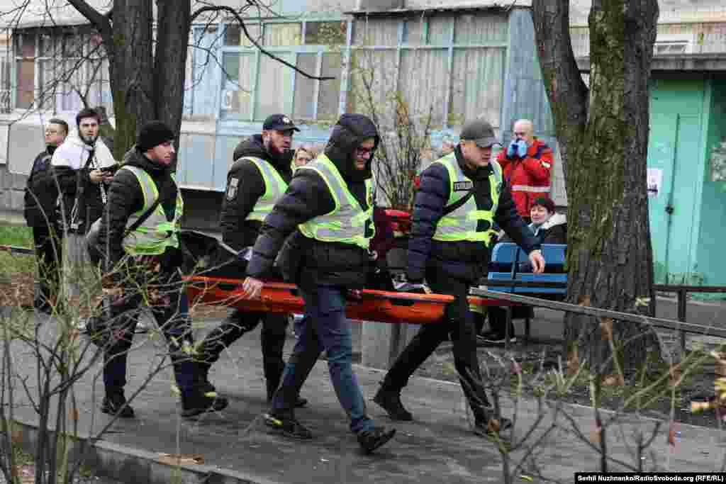 Рятувальники несуть тіло людини, загиблої унаслідок нової масованої атаки РФ на Київ, 14 листопада 2025 року