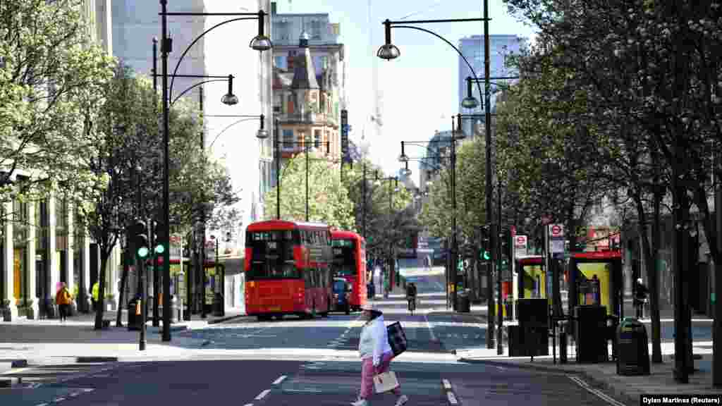 UK - A woman crosses Oxford Street as the spread of coronavirus disease (COVID-19) continues in London, 24Mar2020