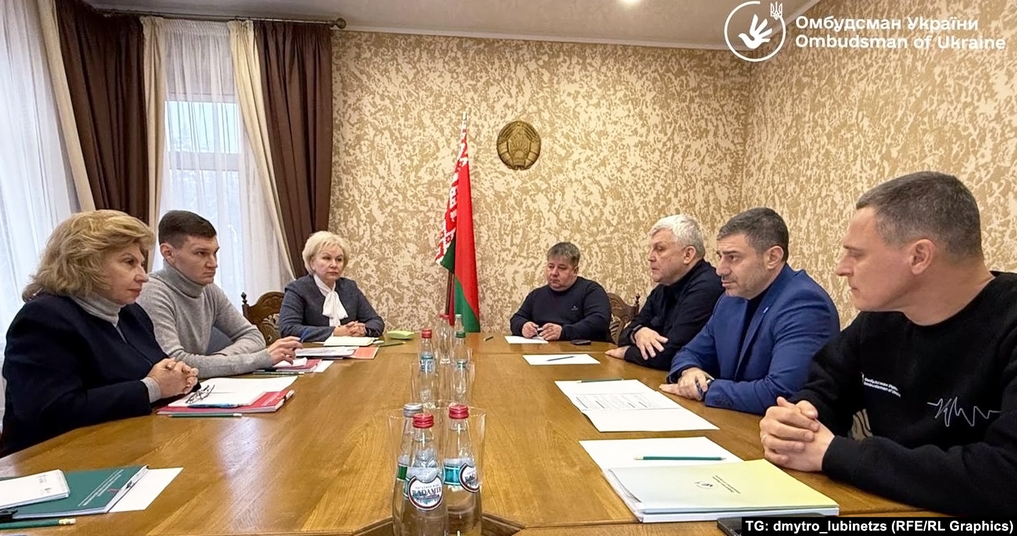 Переговори між Україною та РФ щодо обміну військовополоненими на території Білорусі. У кінці столу під державним прапором і гербом сидить депутатка Палати представників Ірина Костевич, а по ліву руку від неї – чоловік, схожий на офіцера КДБ Валерія Степановича. 31 грудня 2024-го