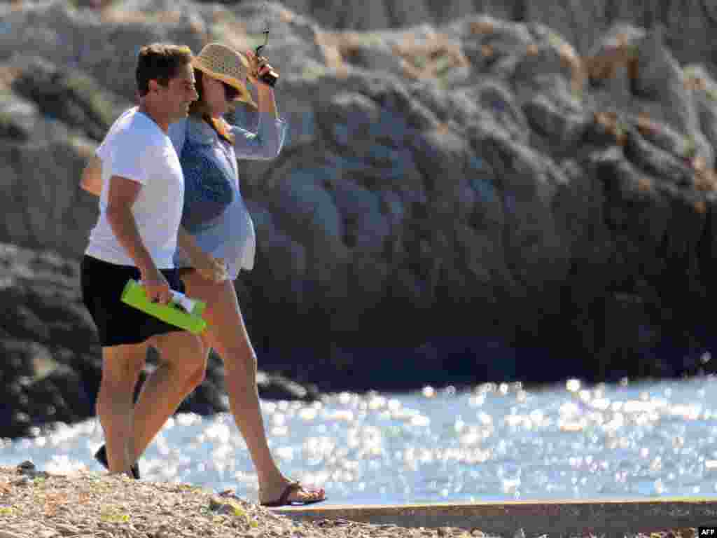 Sarkozy hamilə arvadı Bruni ilə çimərlikdə, 8 iyul 2011. Rəsmi məlumata görə xanım Bruni hamiləliyinə görə Sarkozyni Qafqaz səfərində müşayiət edə bilmir.