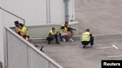 A screen grab taken from video footage shows plain clothes police officers taking cover in the car park of the Olympia shopping mall.