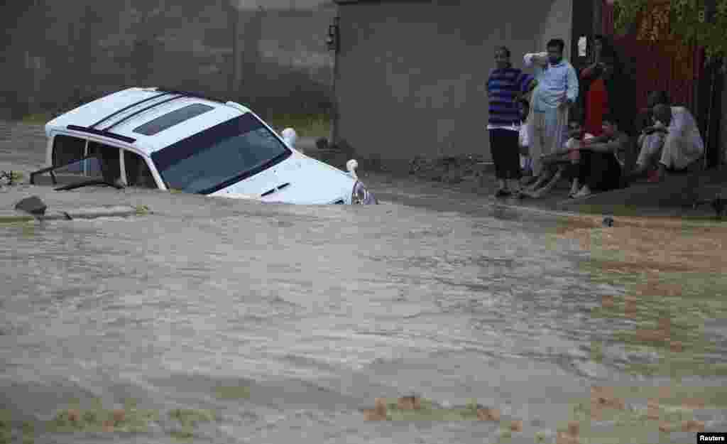 A family waits for rescue workers after their vehicle was submerged in flood waters on the outskirts of Karachi.