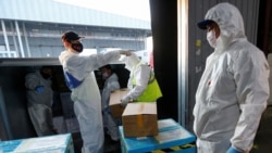 Сотрудники таможни в защитных костюмах разгружают гуманитарную помощь в Алматы. 1 мая 2020 года.