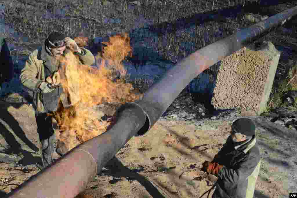 Workers repair a gas pipeline damaged during shelling between Ukrainian forces and pro-Russian militants in the eastern village of Krasnyi Pakhar, in the Donetsk region. (AFP/Aleksandr Khudoteply)