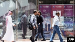 People walk past the Qatar Airways branch in the Saudi capital of Riyadh. 