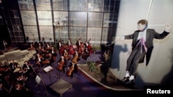 French conductor Hugues Reiner hangs from the roof of the shell-scarred Holiday Inn during a Sarajevo philharmonic concert in 1993.