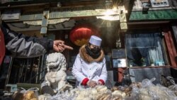 Radnica sa zaštitnom opremom pakuje hranu za kupce na ulici u blizini jezera Houhai, u Pekingu, 17. februar