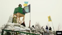 Ukrainian protesters stand guard on a barricade with a recently built watchtower during their continuing protest in Kyiv on January 29.