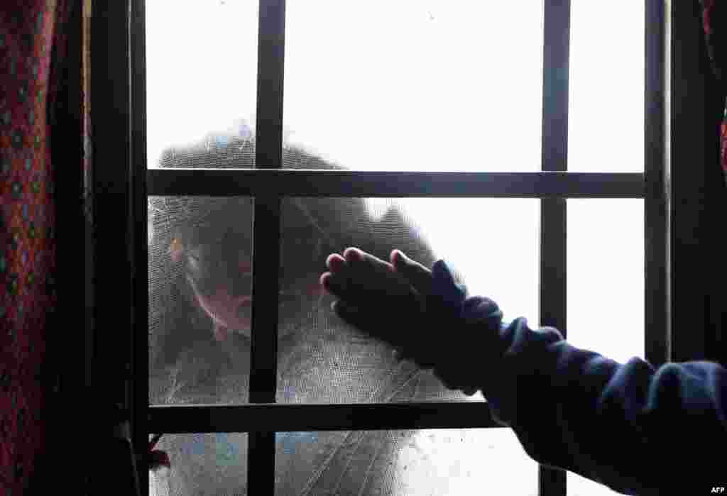 An internally displaced Afghan girl looks in a window at a refugee camp in Kabul. (AFP/Wakil Kohsar)