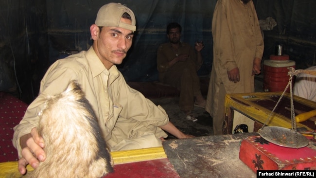 A hashish seller shows off his best-quality product, preserved in goatskin.