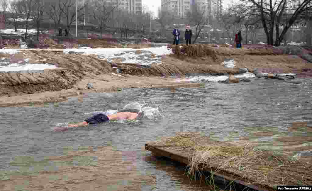 Мужчина, не дождавшись очереди, окунается в проточную воду неподалеку от купели. Алматы, 19 января 2019 года.