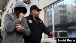 На снимке, сделанном турецким журналистом, – полицейский сопровождает задержанного гражданина России. Адвокаты утверждают, что трое россиян арестованы не после, а накануне теракта в Стамбуле