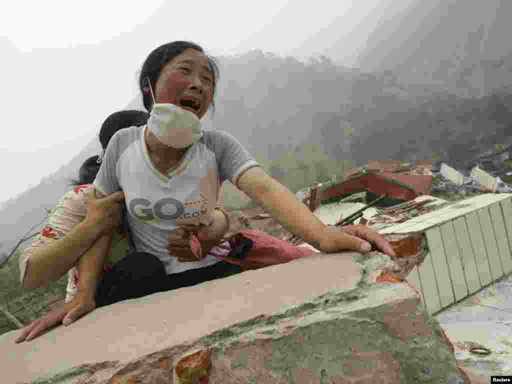 A woman cries as she cannot find her 4-year-old daughter and husband on the top of the ruins of a destroyed school in earthquake-hit Beichuan county, Sichuan province, May 17, 2008. Thousands of Chinese fled to the hills on Saturday amid fears a lake formed near the epicentre of this week's earthquake would burst its banks. The water level at the lake formed after aftershocks blocked a river was rising rapidly in Beichuan and "may burst its bank at any time", the official Xinhua news agency said. REUTERS/Jason Lee (CHINA)
