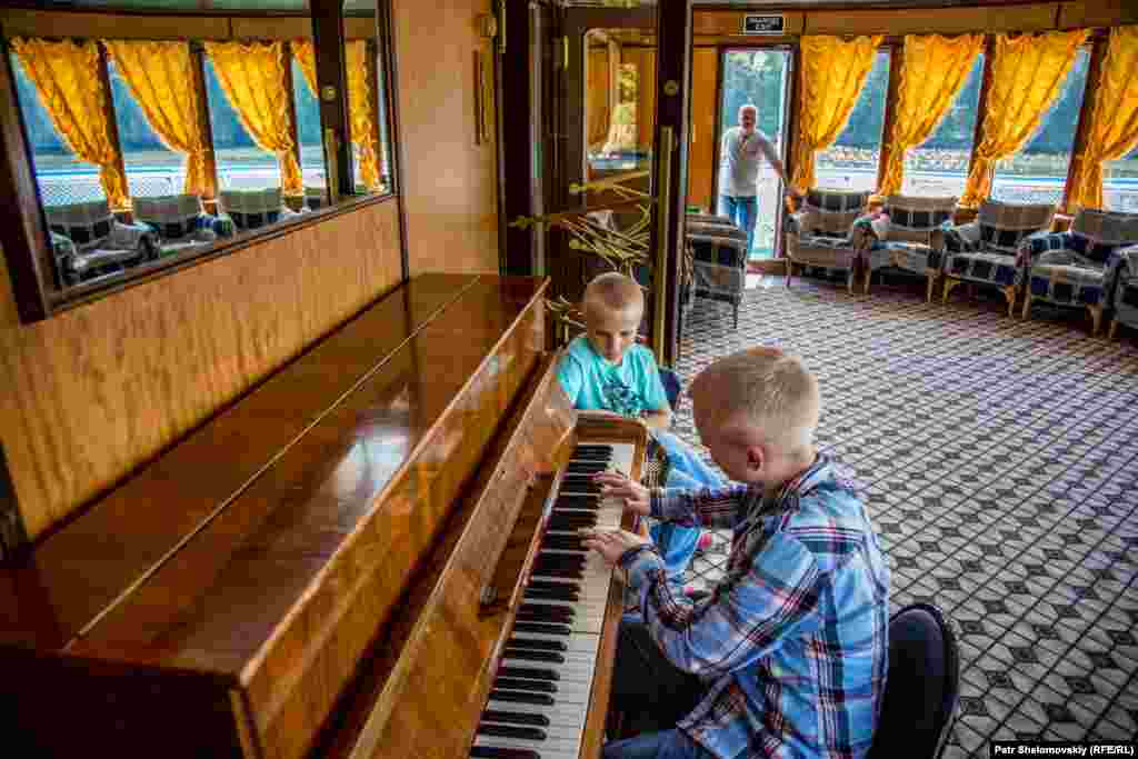 Children play piano on board a boat that has been converted into a hotel.