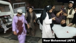 Men carry a wounded man onto a stretcher outside a hospital following a car bomb in Lashkar Gah, the capital of Helmand province on March 23.