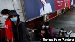 People wearing protective masks walk in a shopping district following an outbreak of the coronavirus in Beijing on March 25.