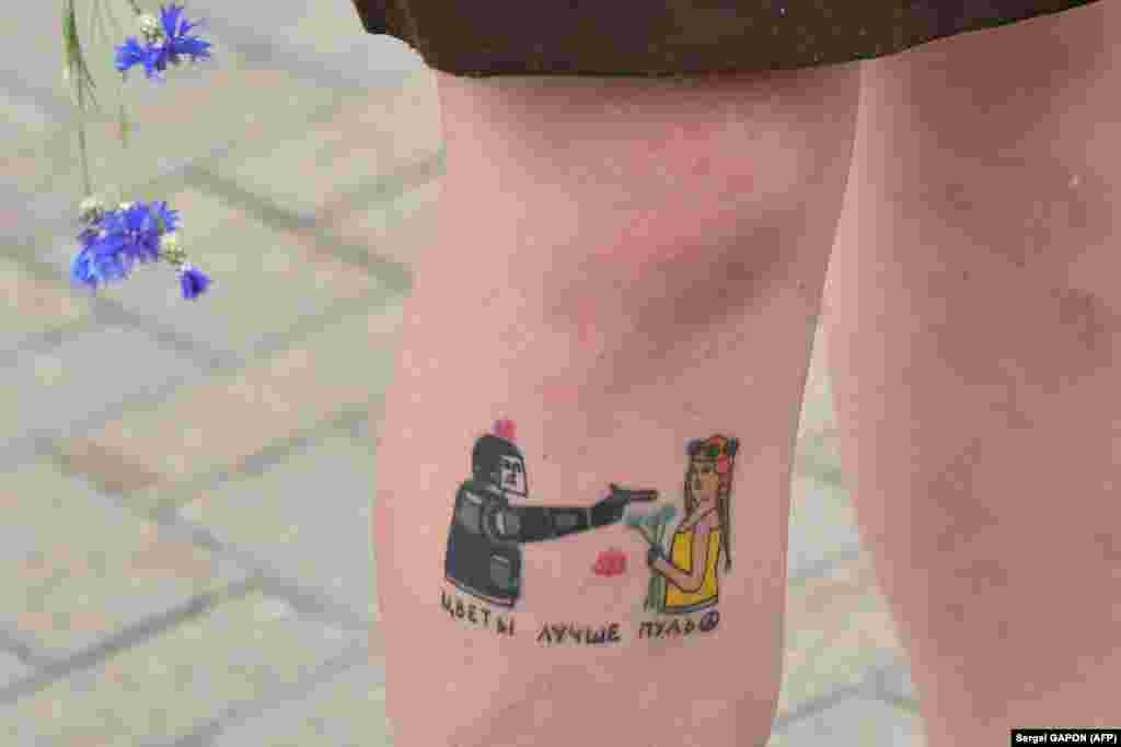Një grua gjatë një proteste më 13 gusht në Minsk, ka shfaqur tatuazhin që ka bërë në këmbën e saj ku thuhet: &ldquo;Lulet janë më të mira se plumbat&rdquo;.