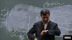 Former Iranian President Mahmud Ahmadinejad looks at his watch in front of the chalkboard in a university lecture hall. (file photo)