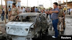 Members of the Kurdish security forces inspect the site of a suicide bombing attack in Kirkuk on June 25.