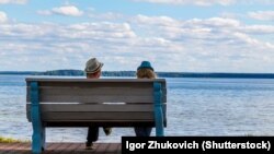 Belarus - Couple in love is resting on a bench by the lake in sunny summer weather. Lake Naroch, undated