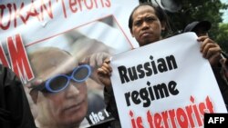 A member of Indonesia's Hizb ut-Tahrir holds a placard in front of a portrait of Russian Prime Minister Vladimir Putin during a protest outside the Russian Embassy in Jakarta.