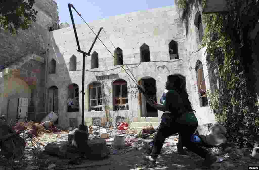 A Free Syrian Army fighter uses a catapult to launch a homemade bomb in the Bab al-Nasr neighborhood of Aleppo. (Reuters/Muzaffar Salman)