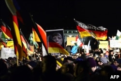 Marchers at the January 12 rally in Dresden, organized by German right-wing populist movement Pegida (Patriotic Europeans Against the Islamization of the Occident), hold up German flags and a doctored image of German Chancellor Angela Merkel.