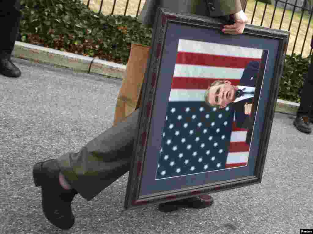 A member of the White House staff walks off with a portrait of outgoing U.S. President George W. Bush in Washington January 13, 2009. Barack Obama is scheduled to be sworn in as the 44th President of the United States on January 20. REUTERS/Jason Reed 