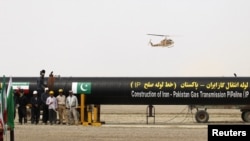 Workers stand by as a security helicopter lands near the pipeline during a ground-breaking ceremony to mark the inauguration of the Iran-Pakistan gas pipeline, in the city of Chahbahar, in March.