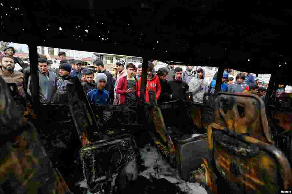 People look at a burned vehicle at the site of car-bomb attack in a busy square at Baghdad&#39;s sprawling Sadr City district on January 2. (Reuters/Ahmad Saad)