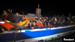Мигранты на шлюпке неподалеку от побережья Ливии ожидают подхода спасательного судна, зафрахтованного испанской правозащитной организацией Proactiva Open Arms в марте 2017 года.