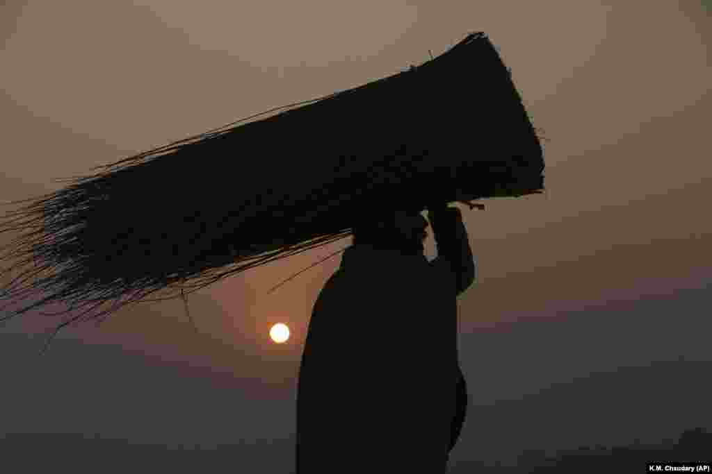 A man carrying straw is silhouetted against the last sunset of 2018 in Lahore, Pakistan. (AP/K.M. Chaudary)