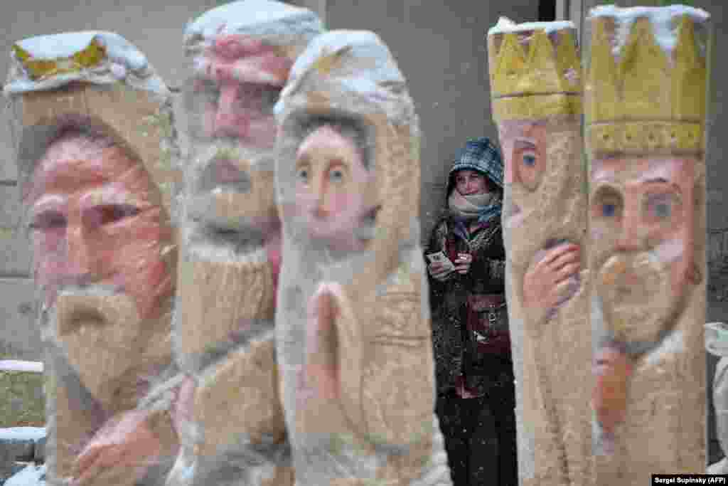 A girl takes a break behind sculptures depicting the Nativity in the center of western Ukrainian city of Lviv. (AFP/Sergei Supinsky)