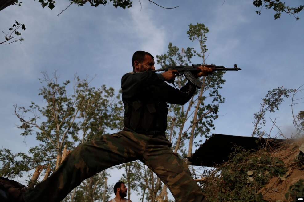 Një luftëtar rebel sirian merr cakun me armën e tij në vijën e frontit kundër forcave të regjimit në periferi të kryeqytetit Damask. &nbsp;