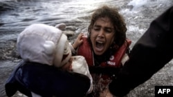 A woman falls into the water with her child as they disembark from a dinghy as refugees and migrants arrive at the Greek island of Lesbos after crossing the Aegean sea from Turkey earlier this month.