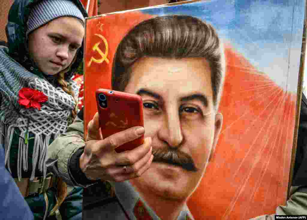 A woman, next to a girl, holds a portrait of former Soviet dictator Josef Stalin and takes a selfie at his grave outside the Kremlin on Red Square in Moscow on March 5 as members of different communist and leftist movements gathered to mark the 66th anniversary of Stalin&#39;s death. (AFP/Mladen Antonov)