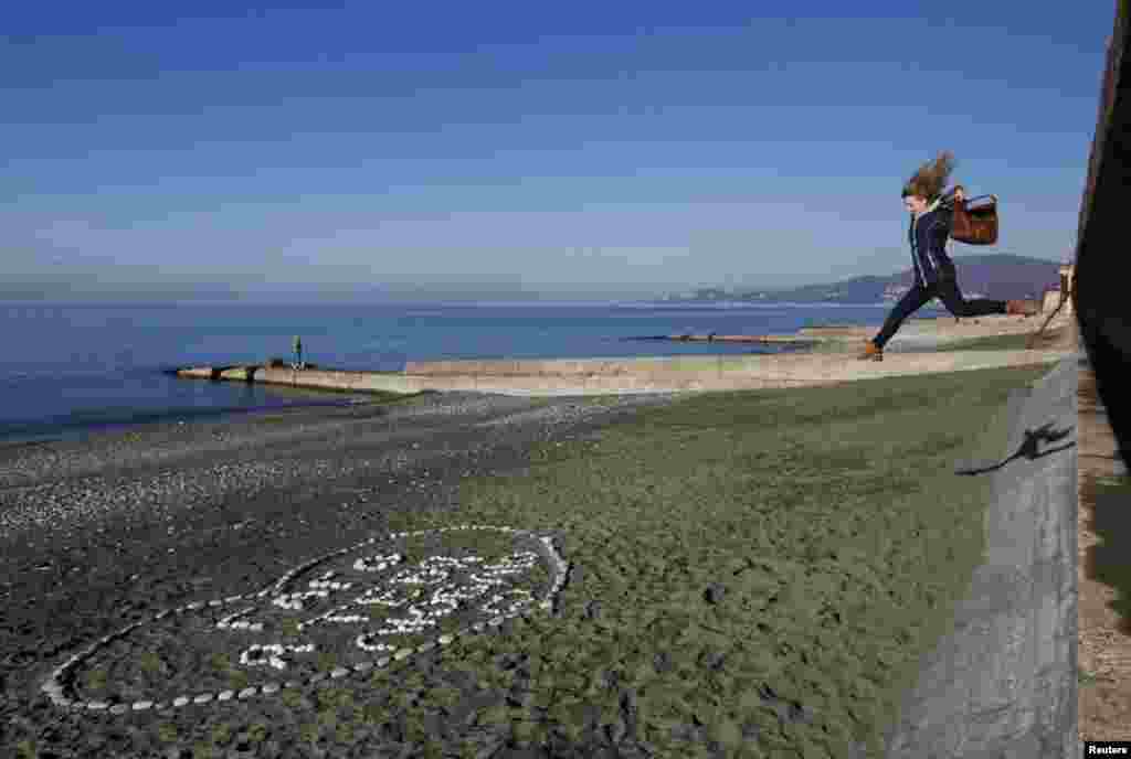 A woman jumps down onto the beach in the Russian Black Sea resort city of Sochi. The city will host the 2014 Winter Olympics in February. (Reuters/Maksim Shemetov)