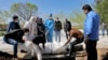 People wearing protective clothing, masks and gloves, attend the funeral of a victim who died of new coronavirus, at a cemetery just outside Tehran, March 30, 2020