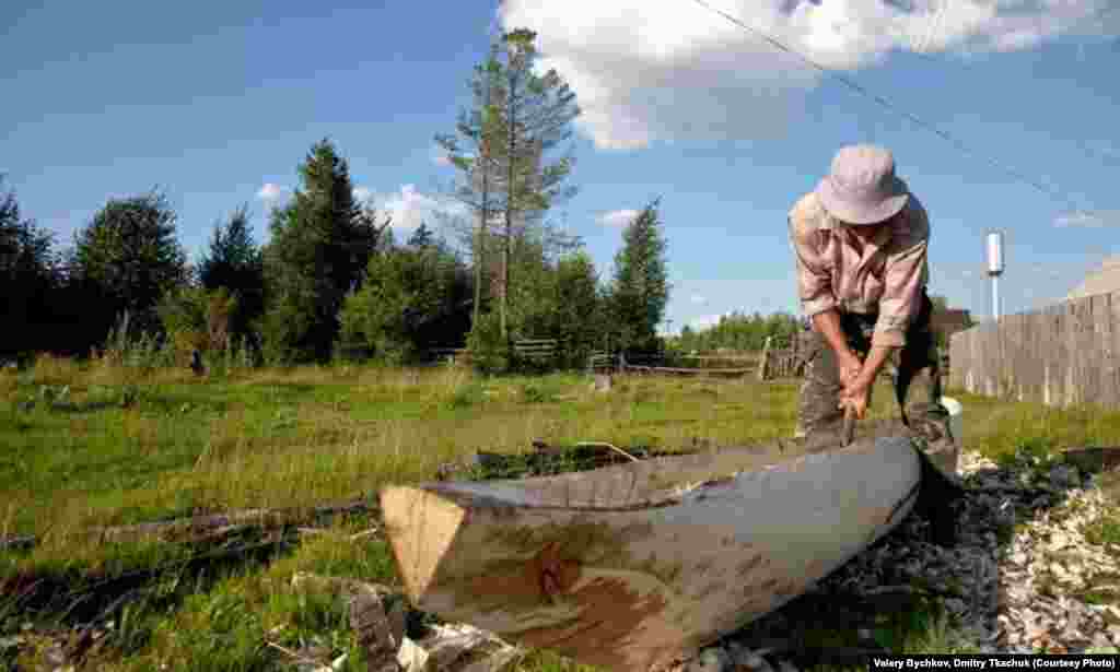 A man hacks a traditional boat by hollowing out a single tree trunk.